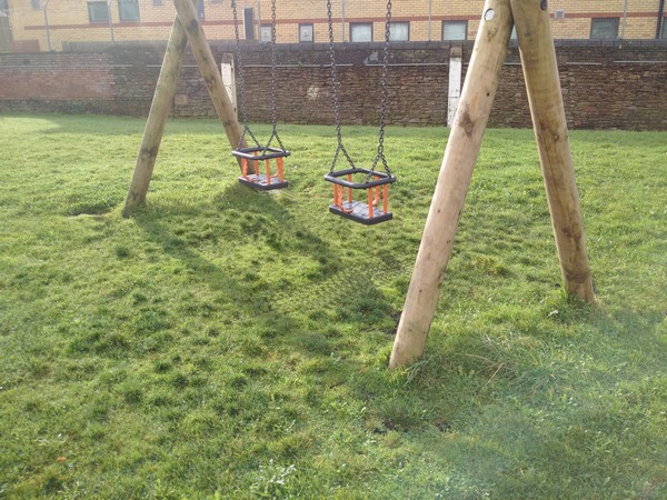 The lush grass completely covered the grass protection mats on the playground under the swings.