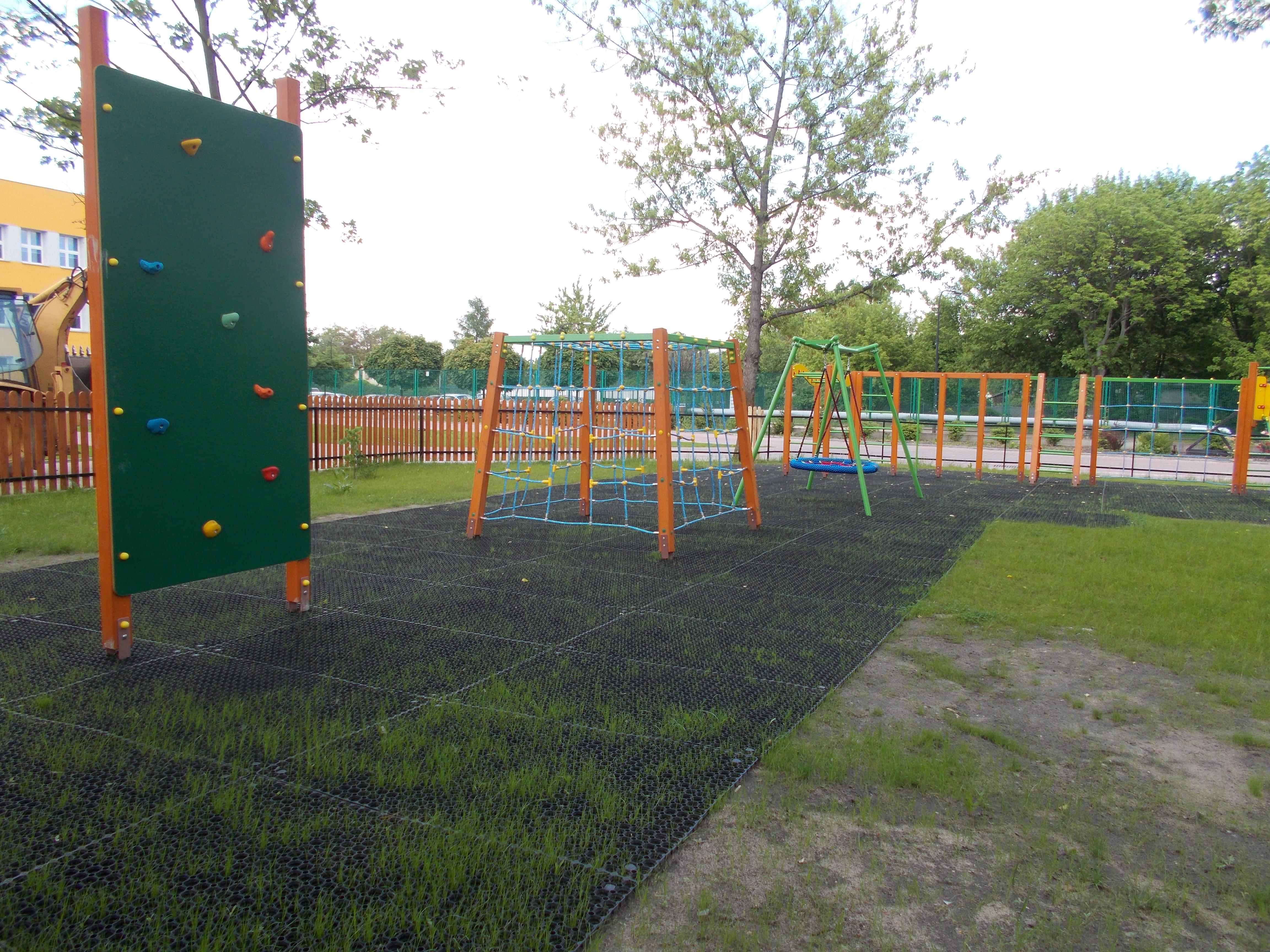 grass protection mats on the Playground visible under the climbing wall. There is a visible difference between the surface covered with mats and without them.